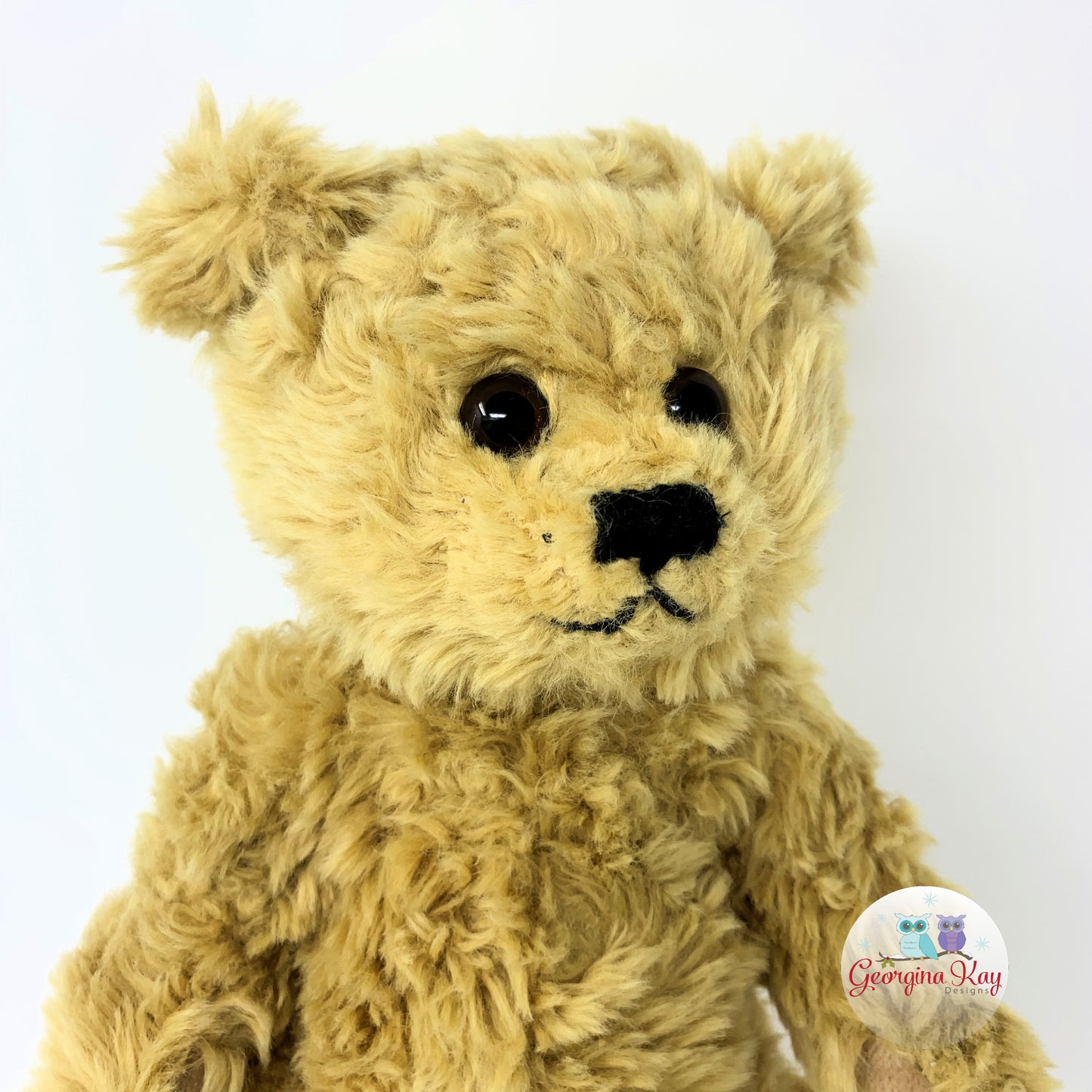 Plush teddy bear with a visible brand logo on a white background