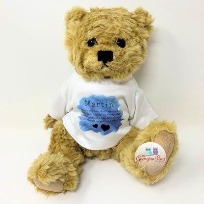 Teddy bear wearing a white shirt with text and a blue heart, on a white background.