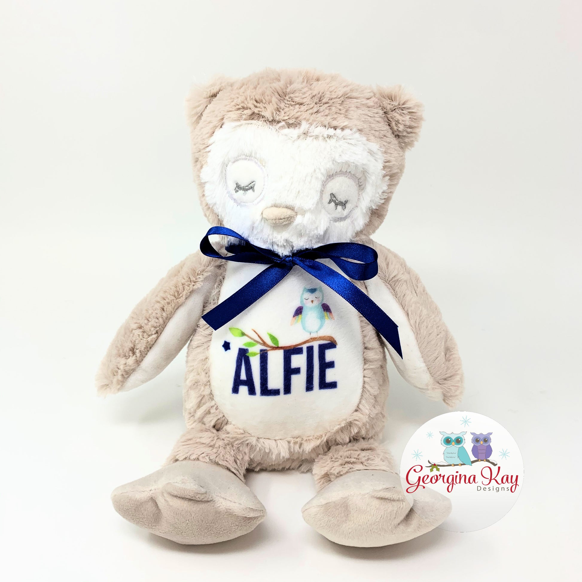 Plush owl toy with a blue ribbon and embroidered name on a white background