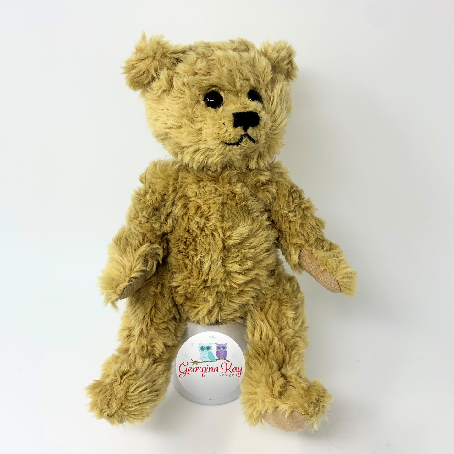 Brown teddy bear with a visible brand logo on a white background