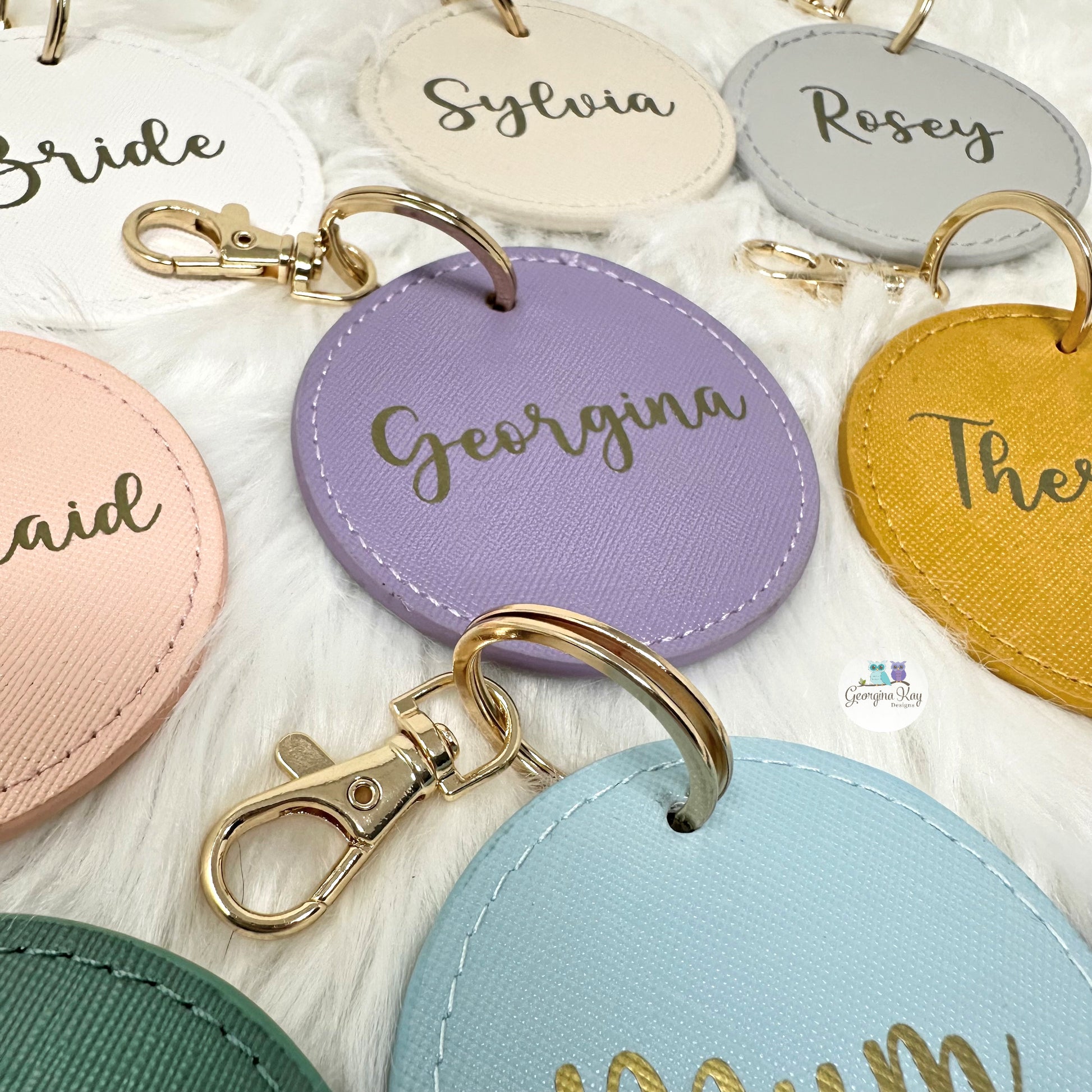 Colorful round keychains with names engraved on a white surface
