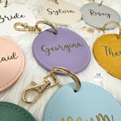 Colorful round keychains with names engraved on a white surface