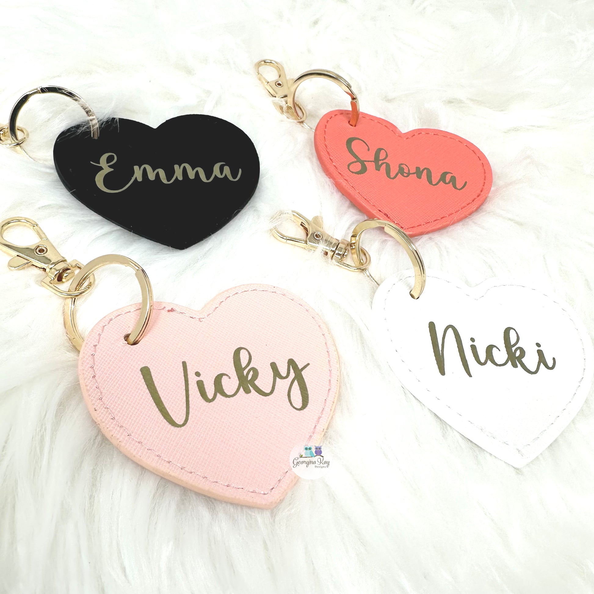 Heart-shaped keychains with names 'Emma', 'Shona', 'Vicky', and 'Nicki' on a white background.