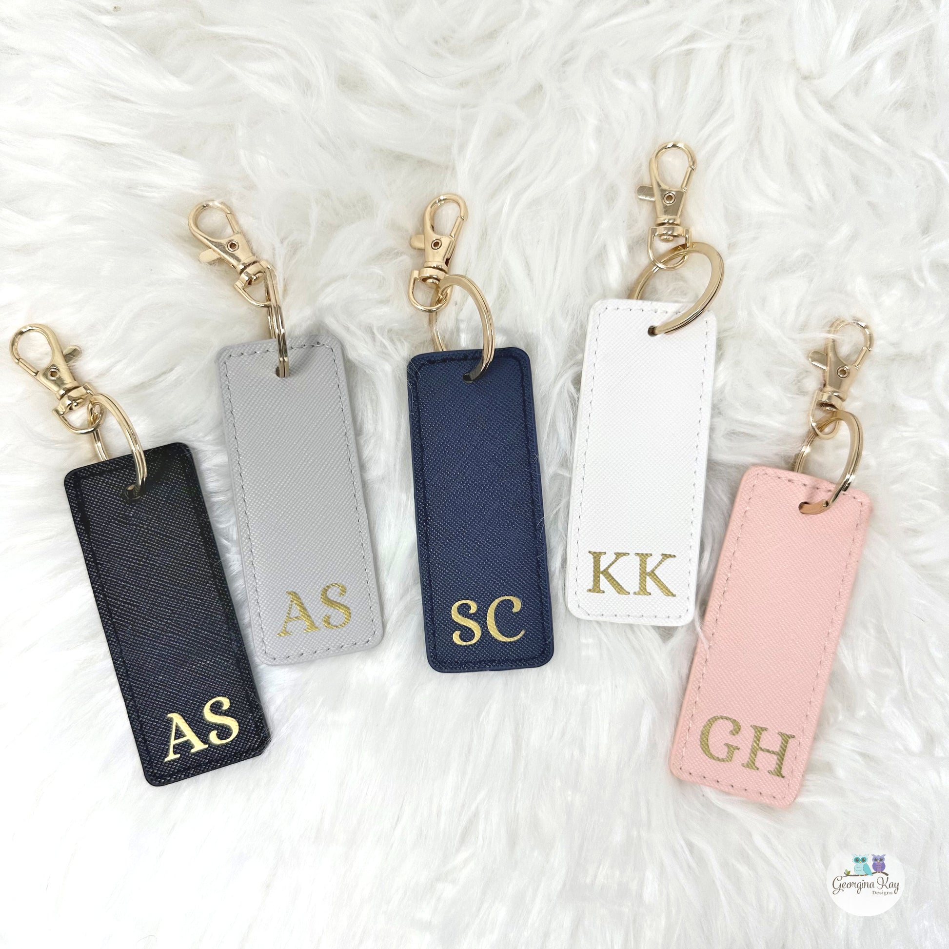 Five keychains with initials on a textured white surface