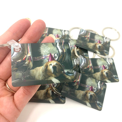 Hand holding multiple keychains with a dog's face printed on them.