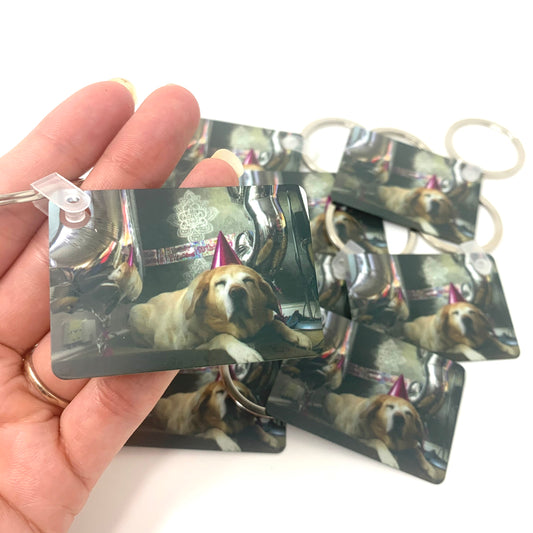 Hand holding multiple keychains with a dog's face printed on them.