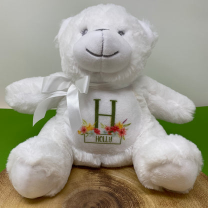 White teddy bear with a floral 'Holly' design on a wooden surface