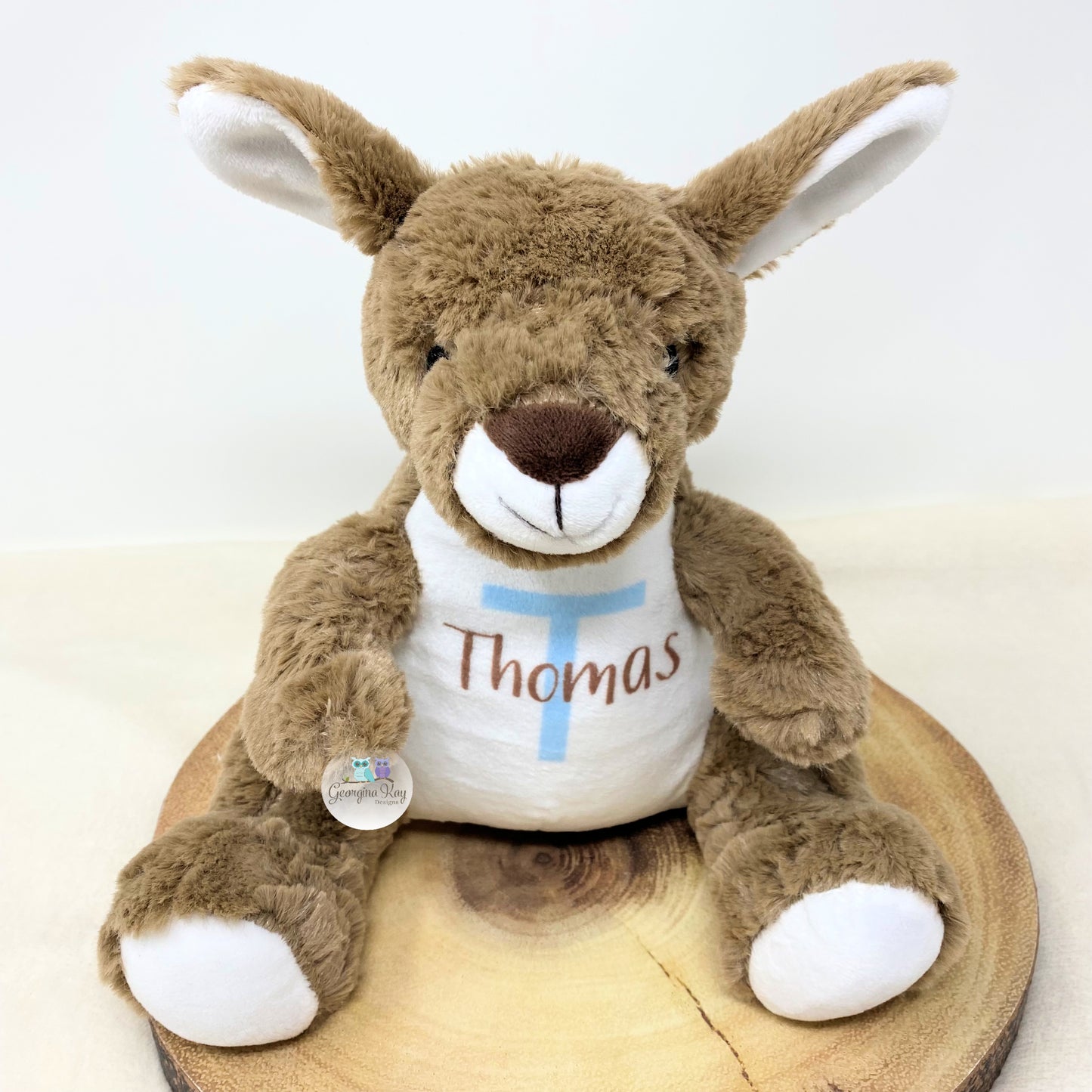 Plush kangaroo toy with a shirt labeled 'Thomas' on a wooden block.