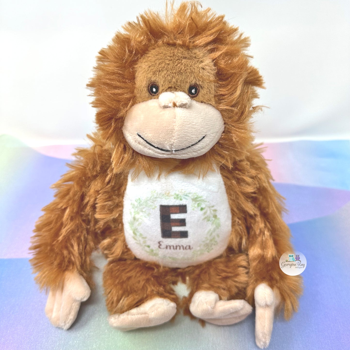 Plush monkey toy with a white belly displaying the letter 'E' and name 'Emma' on a colorful background.