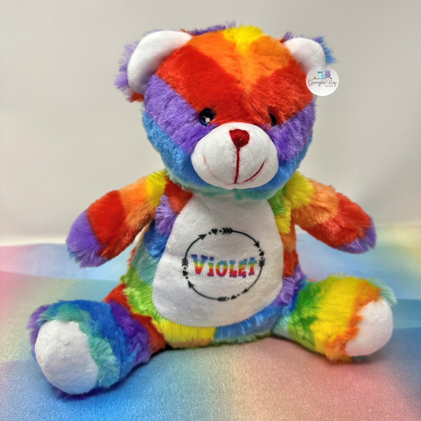 Colorful teddy bear with 'VIOLET' on its belly against a light background