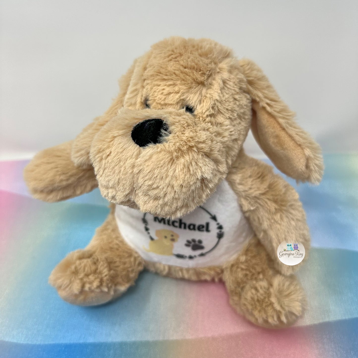 Plush dog toy with a white shirt on a colorful blanket