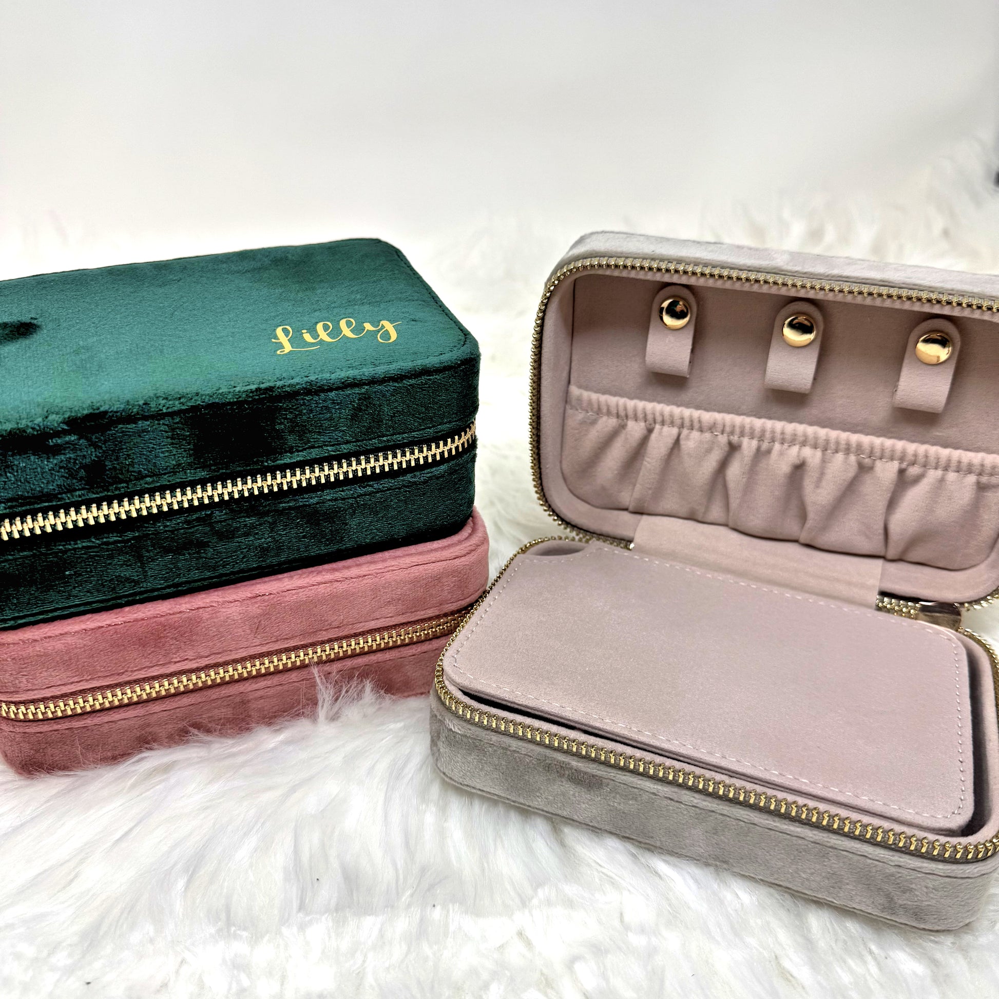 Two jewelry cases, one green and one pink, on a white fluffy surface.