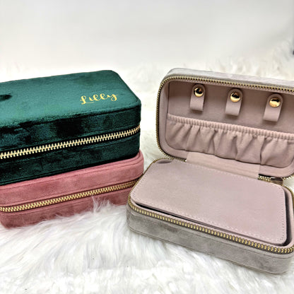 Two jewelry cases, one green and one pink, on a white fluffy surface.