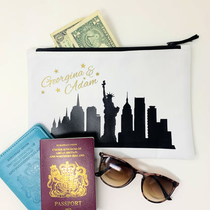 Pouch with a city skyline design, passport, sunglasses, and money on a white background