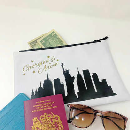 Pouch with city skyline design, passport, money, and sunglasses on a white background
