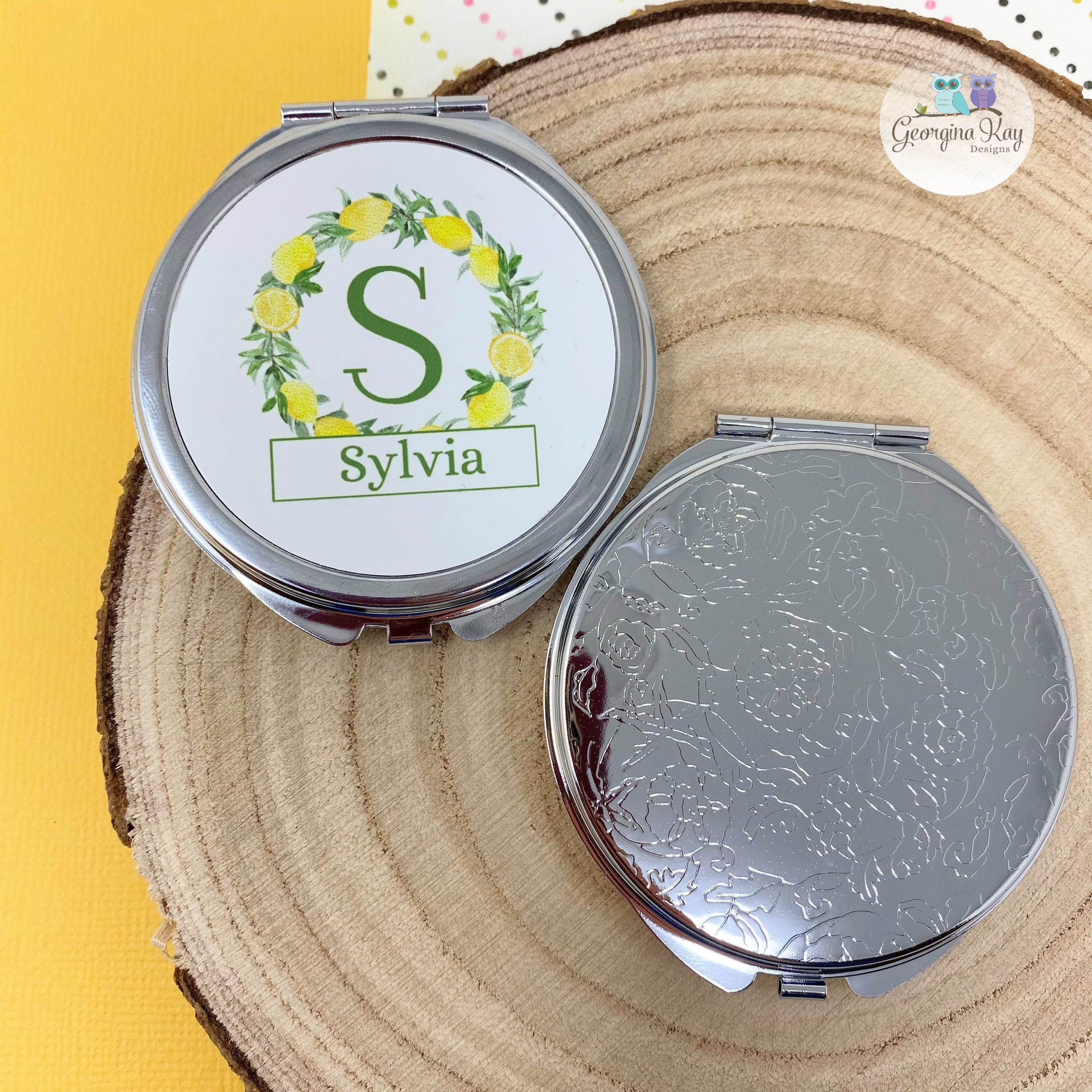 Compact mirror with 'Sylvia' on a wooden surface