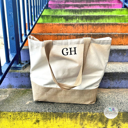Beige tote bag with 'GH' monogram on a colorful staircase