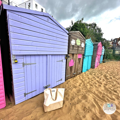 Colorful beach huts on a sandy beach with a bag in the foreground.