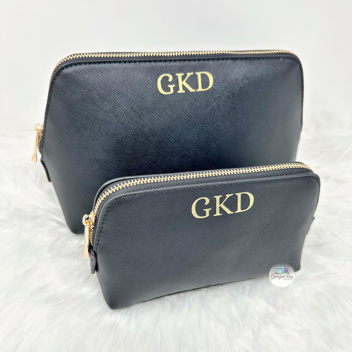 Two black pouches with gold zippers and 'GKD' monogram on a white background.
