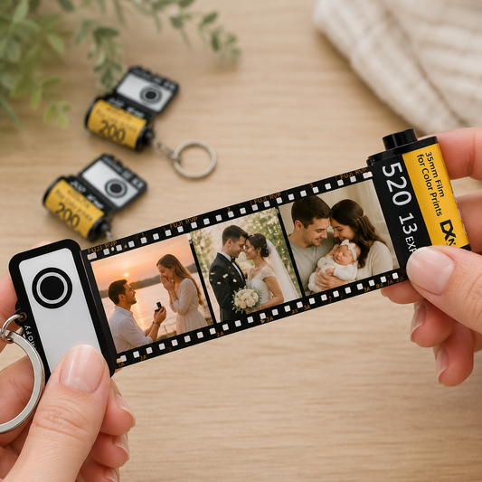 Keychain with a film strip design featuring photos of a couple and a baby, on a wooden surface.