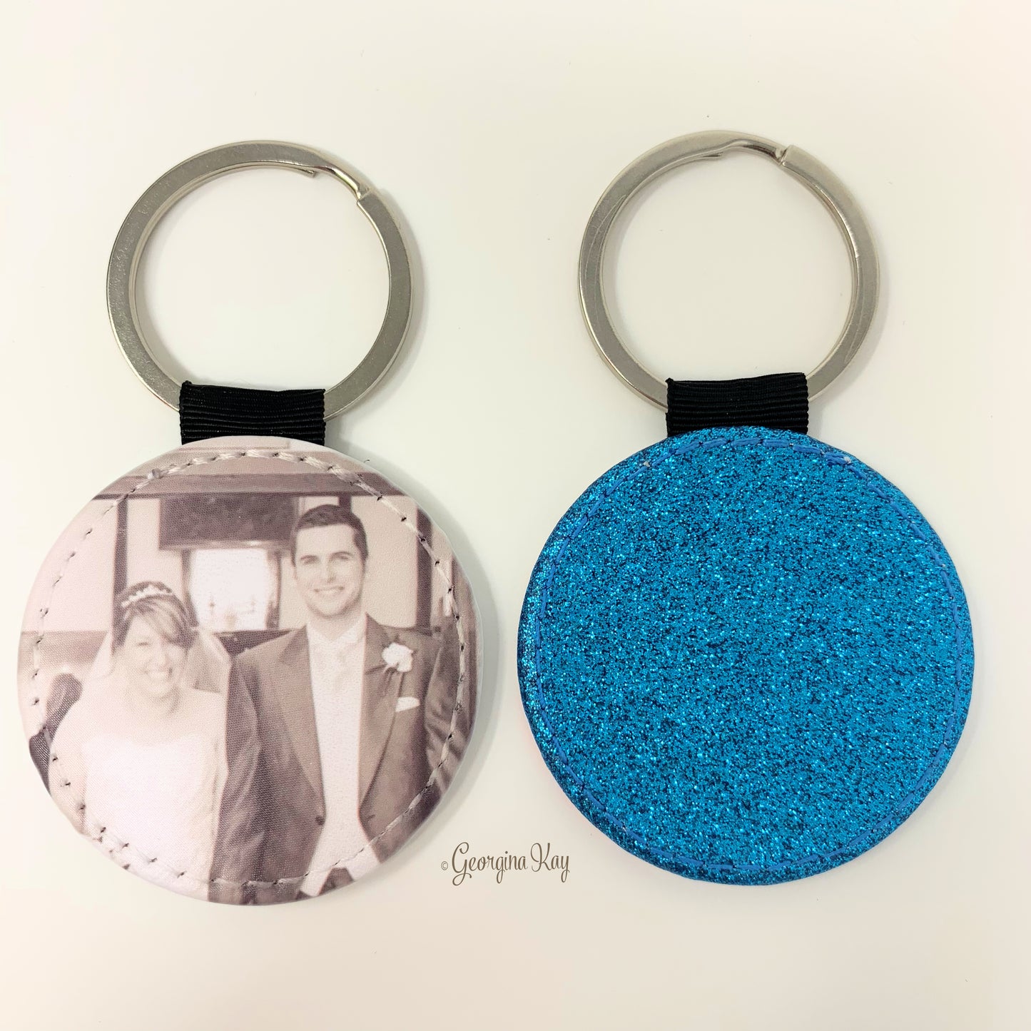 Two keychains, one with a photo of a couple and the other blue glittery, on a white background.