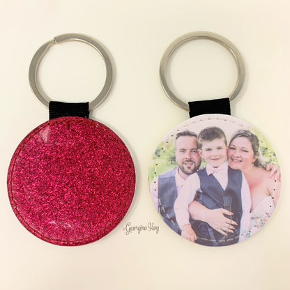 Two keychains, one pink glittery and one with a photo of a family, on a light beige background.