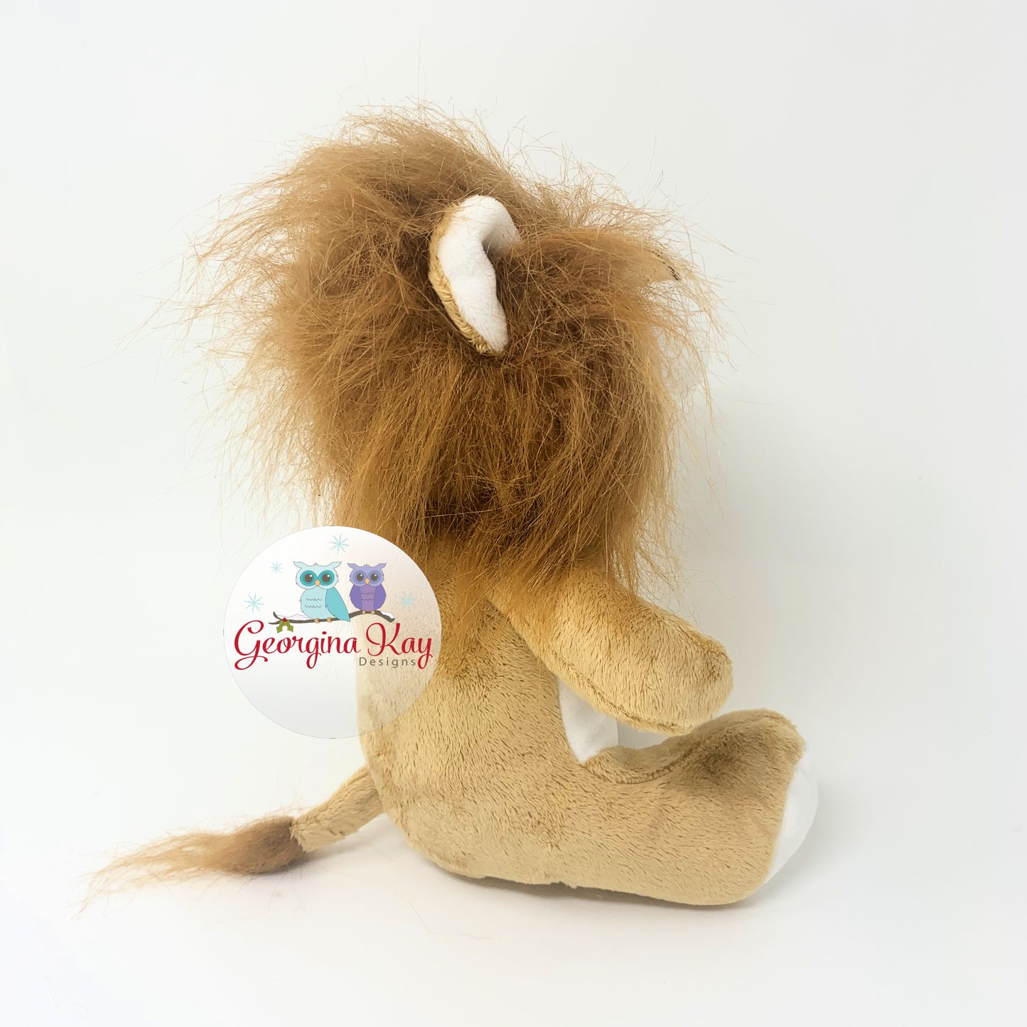 Plush toy lion with a white background, featuring the Georgina Kay Designs logo.