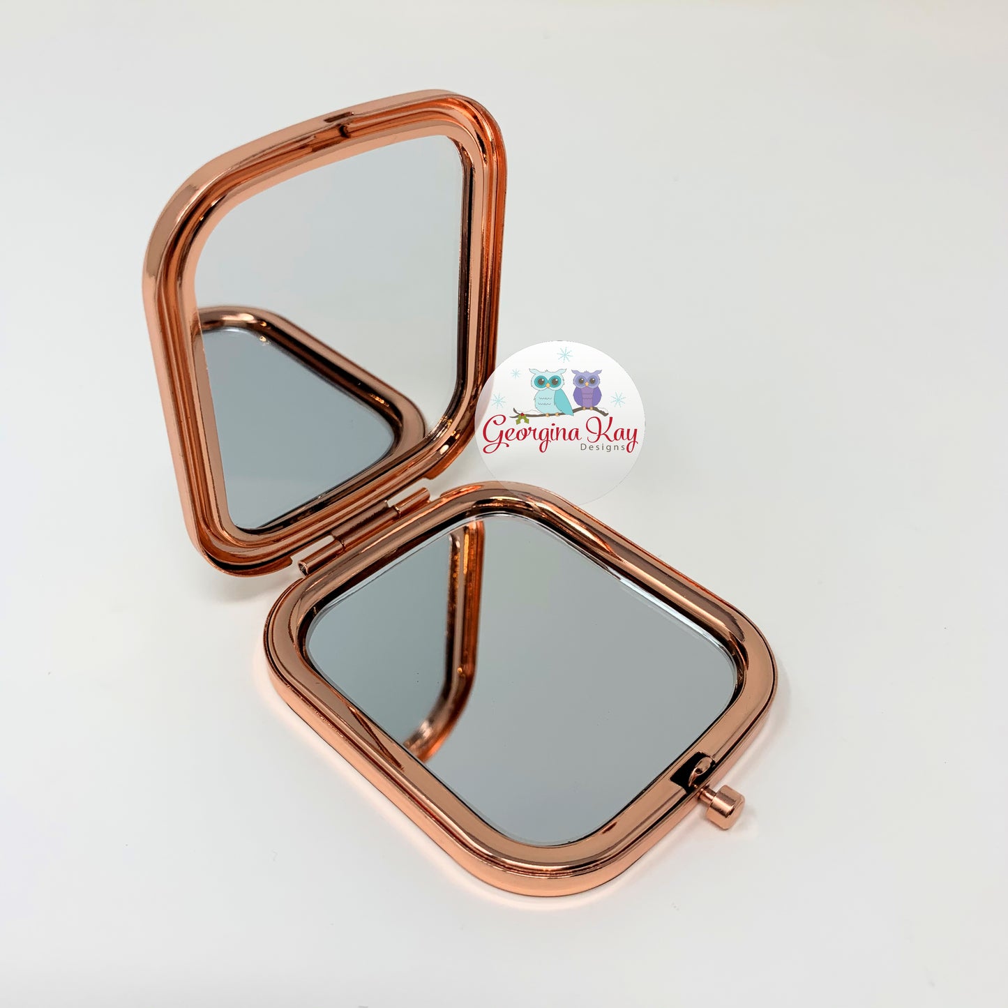 Rose gold compact mirror on a white background with 'Georgina Kay' branding.