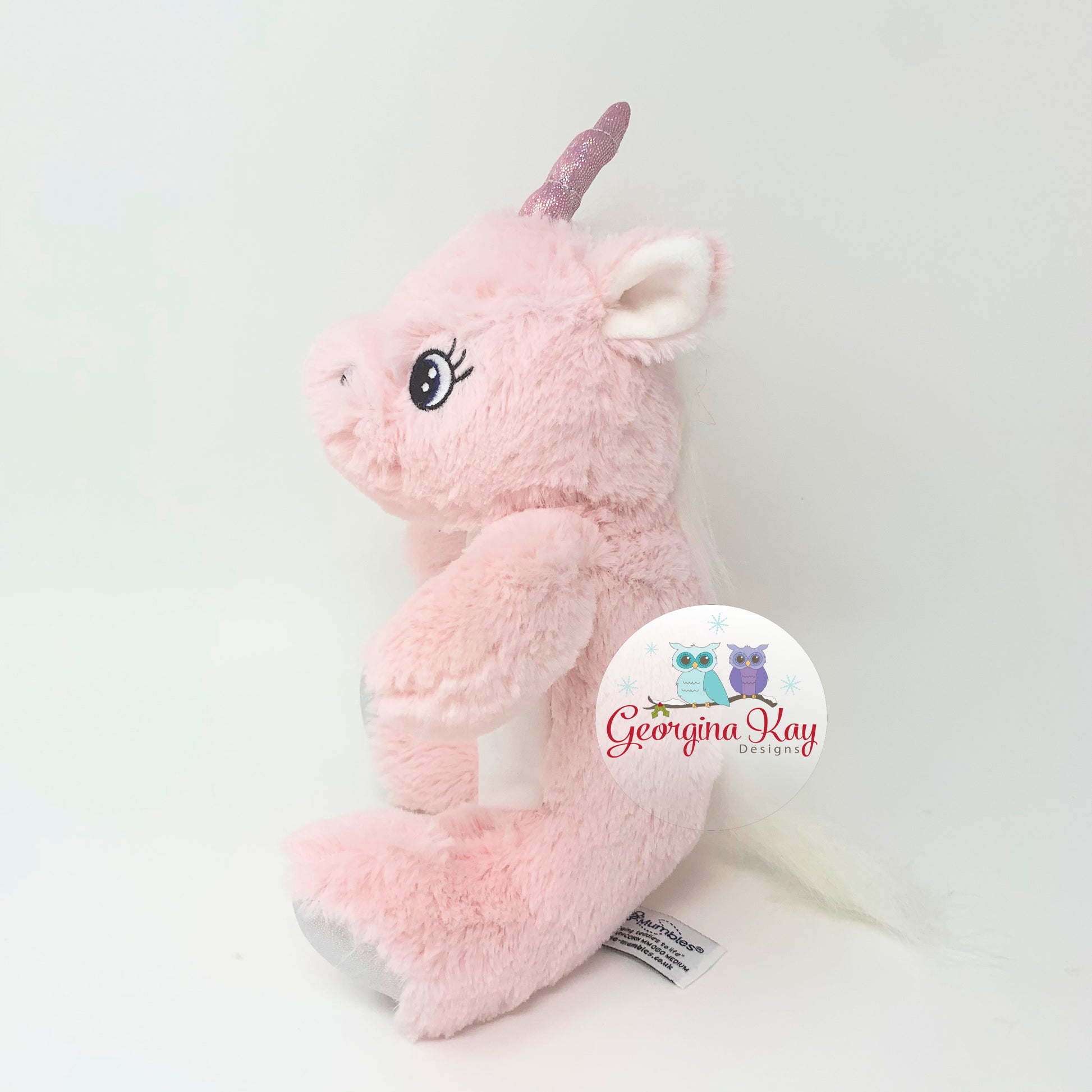 Pink plush unicorn toy with a visible brand logo on a white background