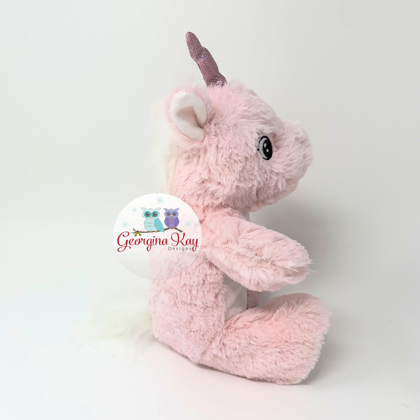 Pink plush toy with a unicorn design on a white background, featuring the brand 'Georgina Kay'.